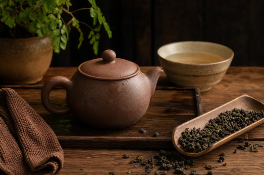 Brown Yixing teapot, oolong leaves, rinse bowl, and tea cloth prepared for seasoning